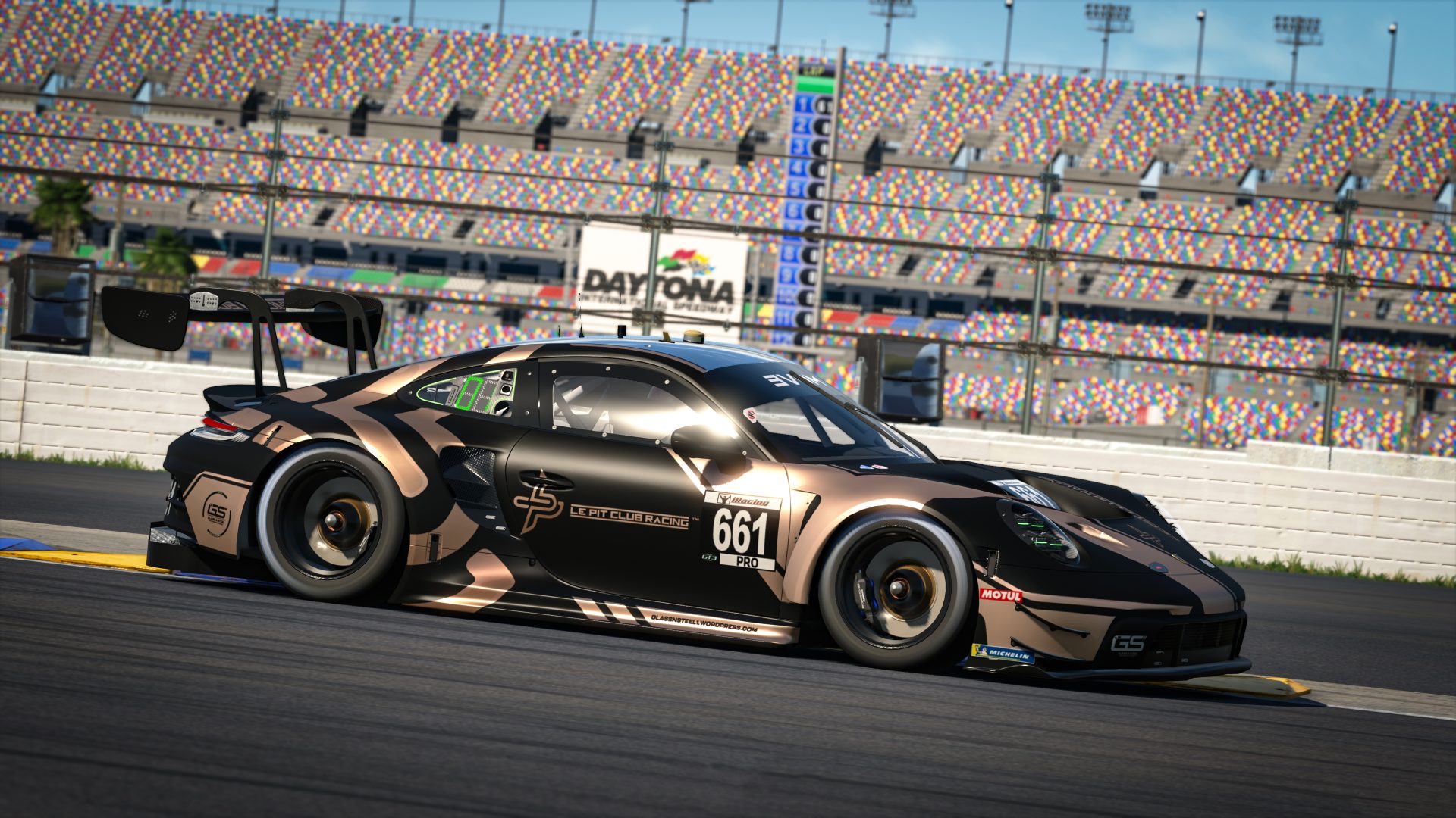 A matte black and bronze Porsche 911 GT3 R race car with number 661 and "Le Pit Club Racing" livery takes a corner at Daytona International Speedway.