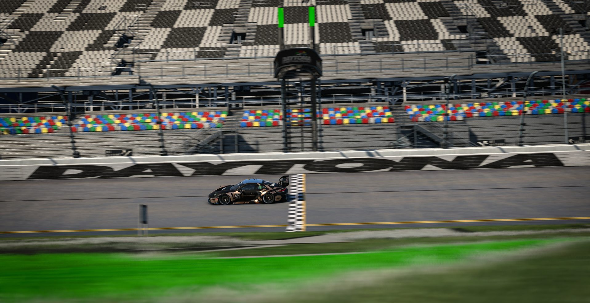 A black Ferrari 488 GT3 race car crosses the start-finish line at Daytona International Speedway with empty grandstands in the background.