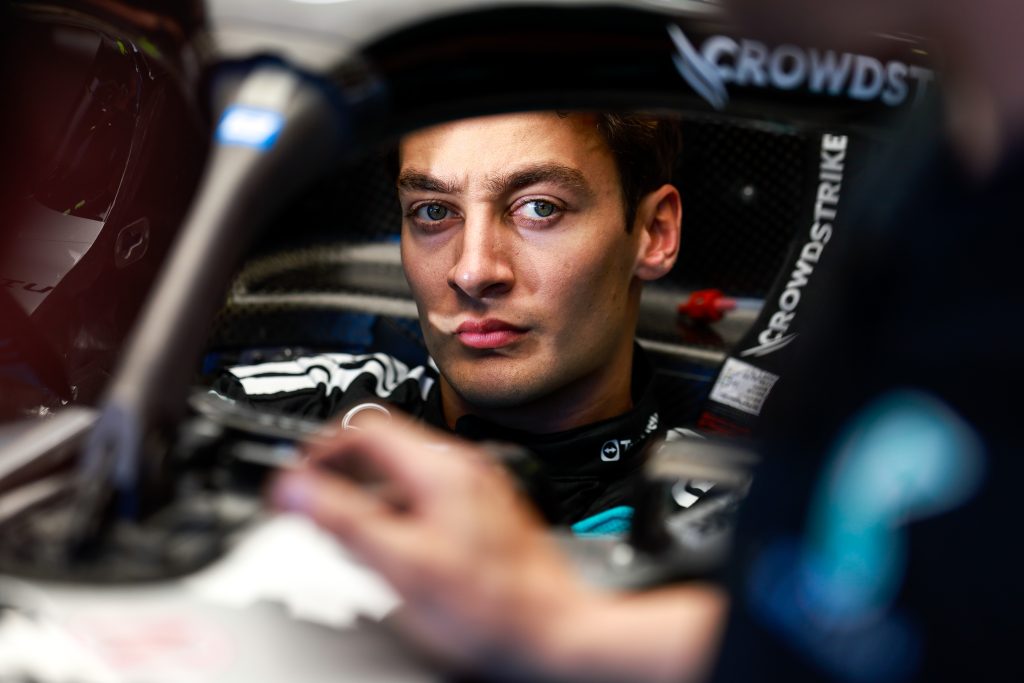 George Russell focuses intently while seated in the Mercedes garage during a Formula 1 race weekend.