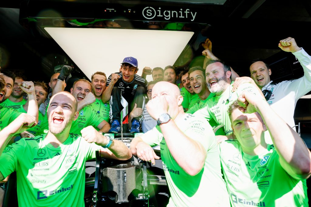 Mercedes driver Kimi Antonelli celebrates with Mercedes team members in the garage.