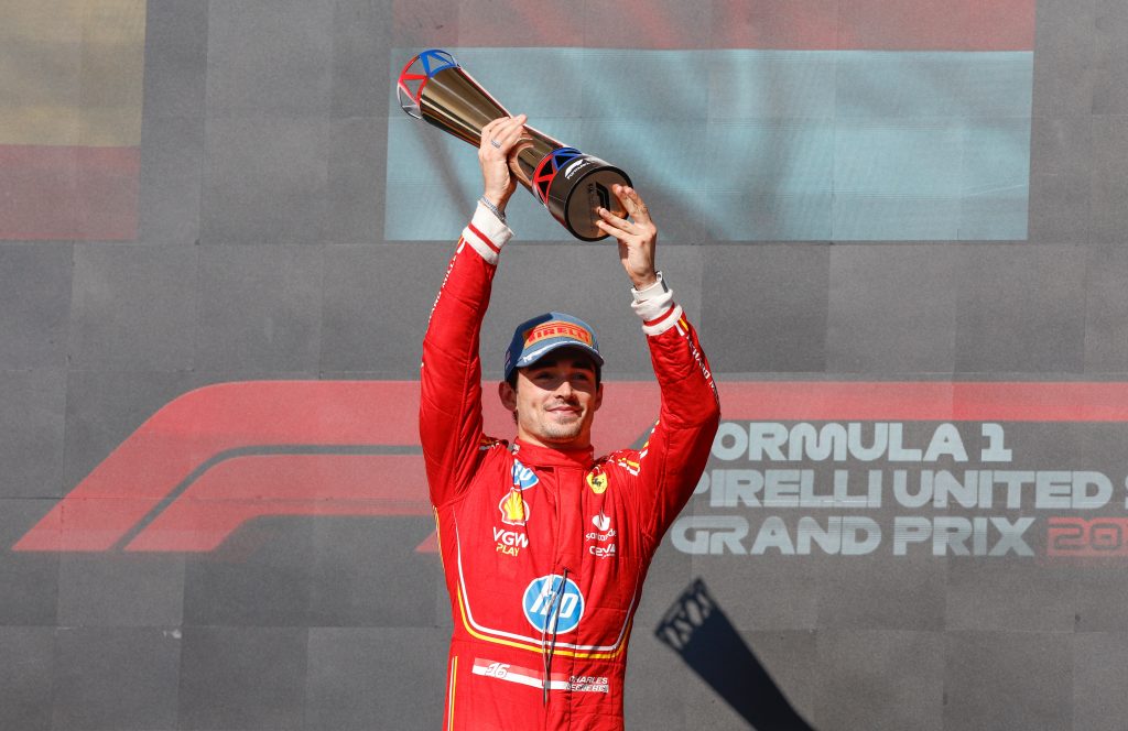 Ferrari driver Charles Leclerc lifts a trophy on the podium.