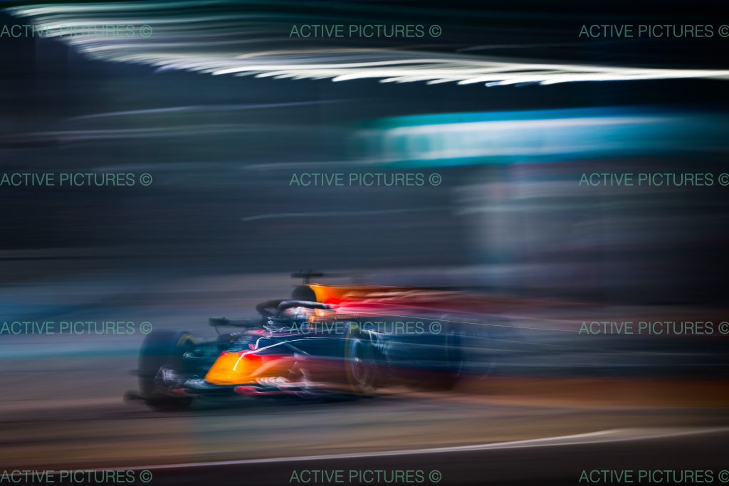 Max Verstappen’s Red Bull (dark blue car), car #3, streaks through the night in a heavily panned shot, the lone car in frame blasting along the Marina Bay street circuit.